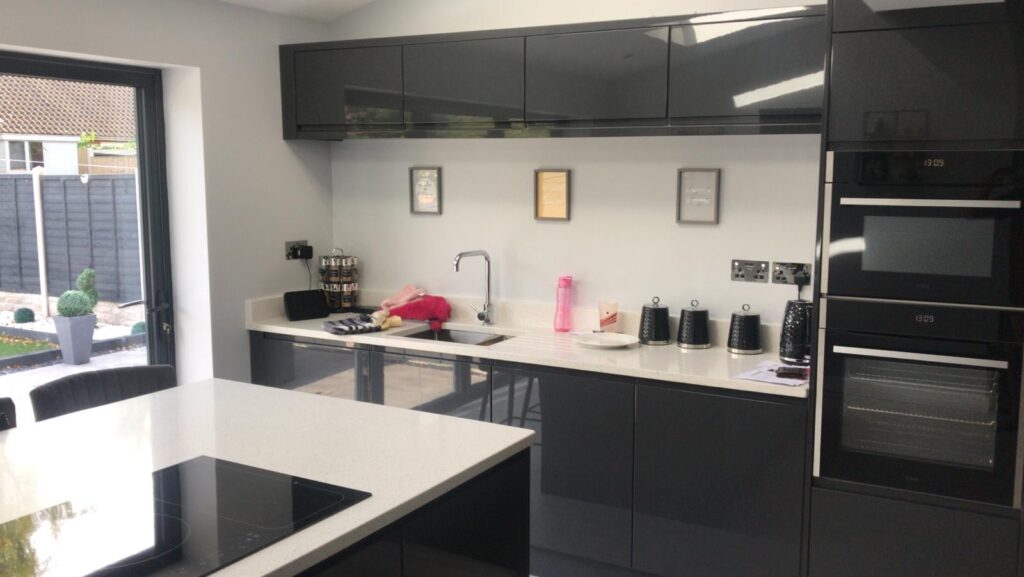 Gloss Anthracite kitchen viewed across island towards kitchen sink with black cupboards above